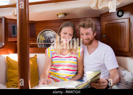 Coppia giovane in barca a vela cabin guardando la mappa di piegatura Foto Stock