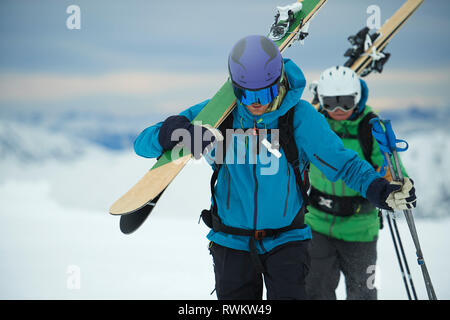 Paesaggio con gli sciatori maschio trascinarsi faticosamente in neve Alpe-d'Huez, Rhone-Alpes, Francia Foto Stock