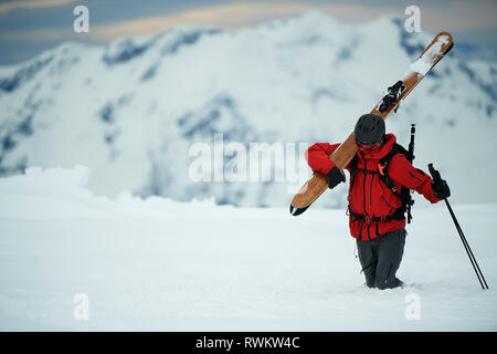 Paesaggio con sciatore maschio trascinarsi faticosamente nella neve profonda, Alpe-d'Huez, Rhone-Alpes, Francia Foto Stock