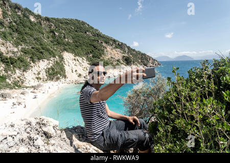 L'uomo prendendo selfie sulla scogliera, Lefkada Island, Leucade, Grecia Foto Stock