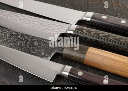 Manici per coltelli e lame di close-up nero sul tagliere di legno Foto Stock