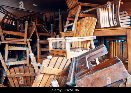 Pila di vecchi obsoleti sedie in legno in uno storage Foto Stock