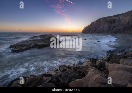 Una lunga esposizione foto di coniatura alte scogliere e le onde si infrangono in un grande rock formazione dopo il tramonto, Dana Point, California Foto Stock