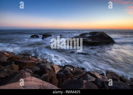 Una lunga esposizione foto di coniatura alte scogliere e le onde si infrangono in un grande rock formazione dopo il tramonto, Dana Point, California Foto Stock