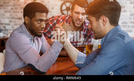 Amici divertendosi, braccio di wrestling, ogni altra in bar Foto Stock