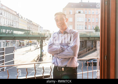 Imprenditore sul balcone che si affaccia sulla strada, Berlino, Germania Foto Stock