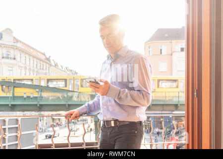 Imprenditore sul balcone che si affaccia sulla strada, Berlino, Germania Foto Stock