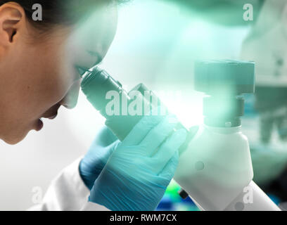 Visualizzazione dello scienziato il campione attraverso il microscopio durante l'esperimento in laboratorio Foto Stock