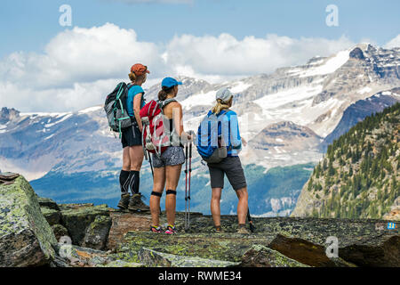 Tre escursionisti femmina su una roccia di montagna che si affaccia mountain vista in background; British Columbia, Canada Foto Stock