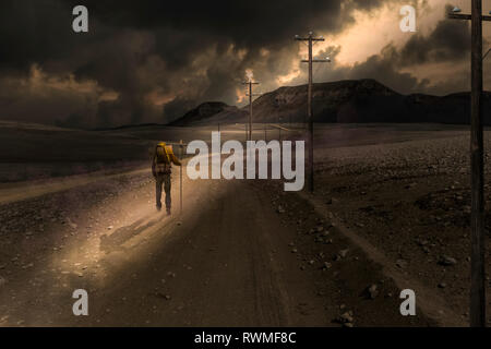 Un uomo cammina lungo una strada vuota in un sole che splende attraverso le nuvole scure, immagine composita Foto Stock