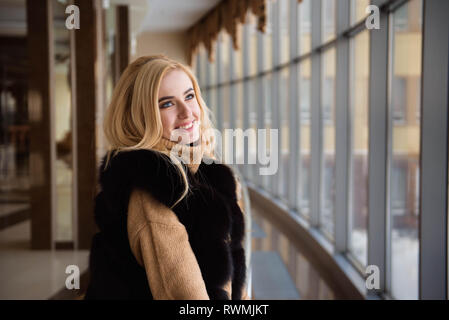 Bella ragazza guarda attraverso la finestra del centro business Foto Stock