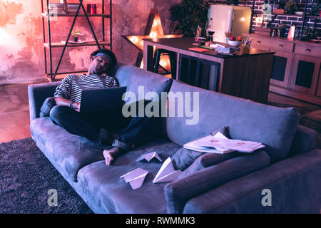Studente maschio ad addormentarsi a causa della musica durante la preparazione per l'esame a destra sul lettino. Foto Stock