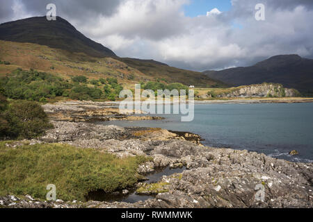 Guardando verso il Loch Buie villaggio lungo una costa rocciosa sull isola di Mull con Ben Buie nella luce solare parziale. Foto Stock