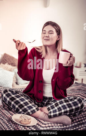 Soddisfatto donna felice di essere estremamente piacevole con gusto di torta Foto Stock