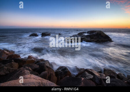 Una lunga esposizione foto di coniatura alte scogliere e le onde si infrangono in un grande rock formazione dopo il tramonto, Dana Point, California Foto Stock