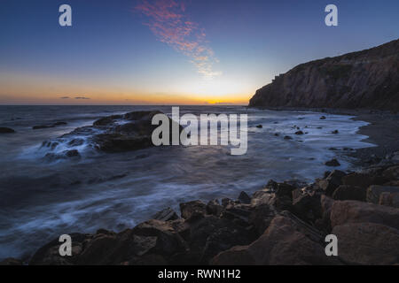 Una lunga esposizione foto di coniatura alte scogliere e le onde si infrangono in un grande rock formazione dopo il tramonto, Dana Point, California Foto Stock