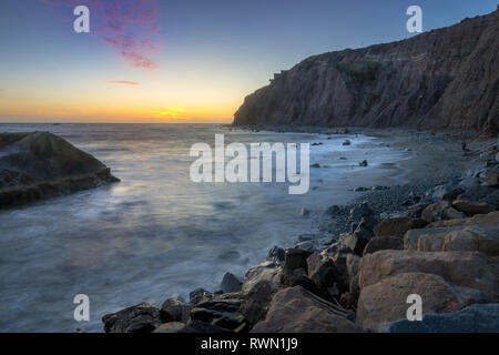 Una lunga esposizione foto di coniatura alte scogliere e le onde si infrangono in un grande rock formazione dopo il tramonto, Dana Point, California Foto Stock