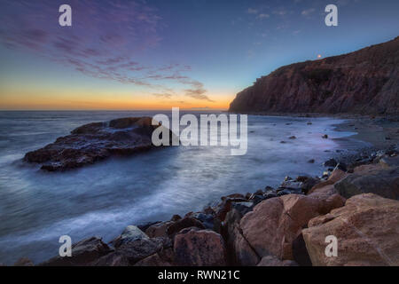 Una lunga esposizione foto di coniatura alte scogliere e le onde si infrangono in un grande rock formazione dopo il tramonto, Dana Point, California Foto Stock