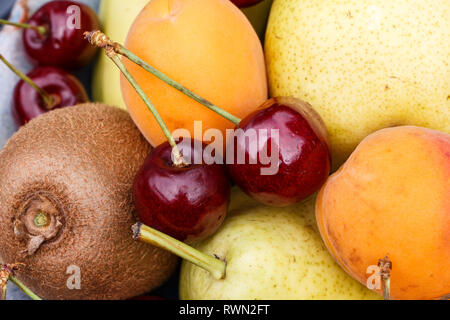 Albicocche, pere, ciliegie e kiwi in una ciotola Foto Stock