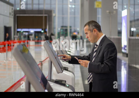 Il passeggero business man in aeroporto controllare nel biglietto al terminale di kiosk Foto Stock