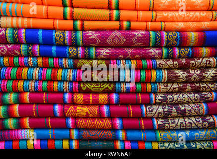 Colorato pila di prodotti tessili sul mercato indigeno di Otavalo, Ecuador. Questi tessuti possono essere trovati nel mondo andino: Perù, Bolivia, Ecuador. Foto Stock