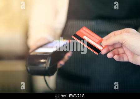Tagliate il colpo di un irriconoscibile uomo pagando per il suo acquisto con carta contactless. Soft focus sulla scheda Foto Stock