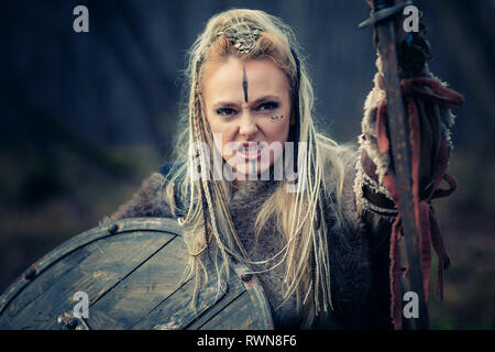 Pazzo furioso viking donna guerriero nell'attacco. Cotica erbosa e di scudo. Close-up verticale. Copertina del libro Foto Stock