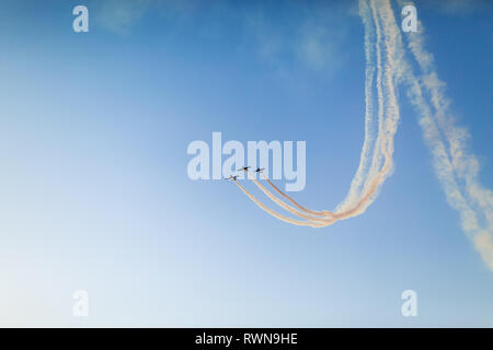 Gli aerei non identificabili esecuzione di volo acrobatico sul cielo blu. Traccia di fumo dietro Foto Stock