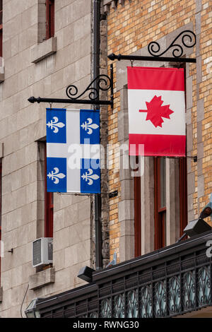 Bandiera nazionale canadese e bandiera provinciale del Quebec appesa da parentesi d'insegna vintage su un edificio in mattoni a Quebec, Canada Foto Stock