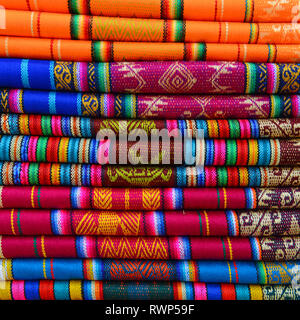 Un mucchio di Ande tradizionali prodotti tessili nei locali la domenica Mercato di Otavalo, Ecuador. Questi tessuti si trovano anche in Perù e in Bolivia. Foto Stock