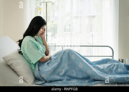Asian giovane donna pazienti giacente in camera. Pazienti asiatici aveva forti mal di testa in ospedale. Foto Stock