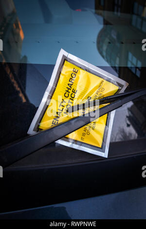 Giallo adesivo per parabrezza contenente una penalità fissa Parcheggio Avviso di carica per il parcheggio illegale ammenda tassa bloccato su di un parabrezza di automobile. Foto Stock