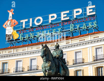 Il Landmark Tio Pepe segno sopra Piazza Puerta del Sol con la statua di Carlo III Carlo III di Spagna a Madrid Foto Stock