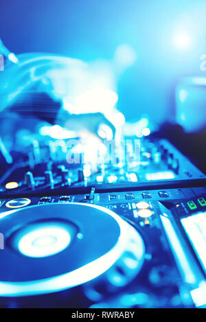 Morbida vista di man mano disc jockey di miscelazione e miscelazione di brani musicali sul suo ponte nelle tenebre di una parte o di un night club.Copia spazio per il testo. Foto Stock