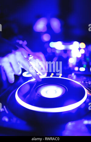 Morbida vista di man mano disc jockey di miscelazione e miscelazione di brani musicali sul suo ponte nelle tenebre di una parte o di un night club.Copia spazio per il testo. Foto Stock