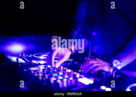 Morbida vista di man mano disc jockey di miscelazione e miscelazione di brani musicali sul suo ponte nelle tenebre di una parte o di un night club.Copia spazio per il testo. Foto Stock