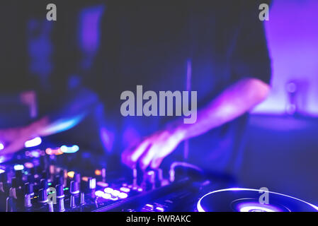 Morbida vista di man mano disc jockey di miscelazione e miscelazione di brani musicali sul suo ponte nelle tenebre di una parte o di un night club.Copia spazio per il testo. Foto Stock