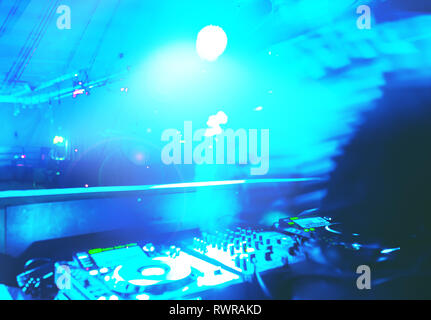 Morbida vista di man mano disc jockey di miscelazione e miscelazione di brani musicali sul suo ponte nelle tenebre di una parte o di un night club.Copia spazio per il testo. Foto Stock