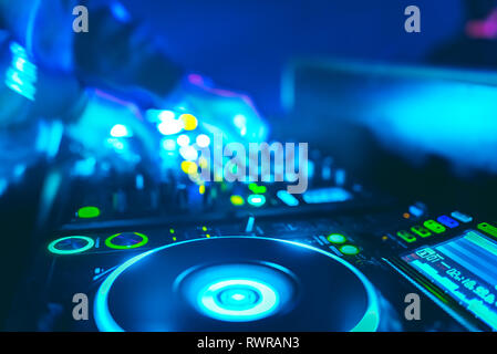 Morbida vista di man mano disc jockey di miscelazione e miscelazione di brani musicali sul suo ponte nelle tenebre di una parte o di un night club.Copia spazio per il testo. Foto Stock