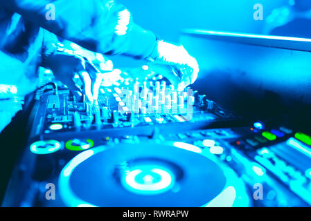 Morbida vista di man mano disc jockey di miscelazione e miscelazione di brani musicali sul suo ponte nelle tenebre di una parte o di un night club.Copia spazio per il testo. Foto Stock