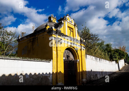 Giallo chiesa cappella con croce storta sotto la nuvola blu cielo, Antigua, Guatemala Foto Stock