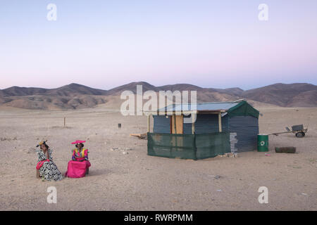 Herero donne siedono al di fuori di una casa in Purros, Regione di Kunene, Namibia. Foto Stock