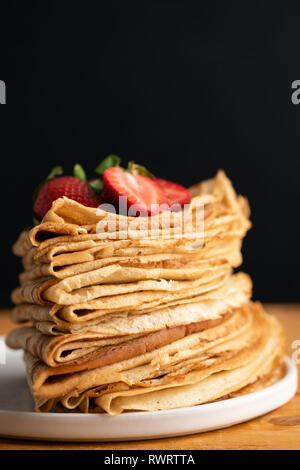 Pila di crepes o blini sul tavolo di legno, sfondo nero. Copia spazio per il testo. Maslenitsa cibo Foto Stock