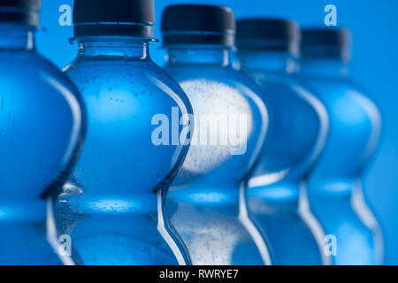 Close up di plastica le bottiglie di acqua con bolle in fila su sfondo blu Foto Stock