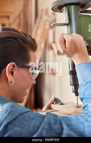 Giovane donna come un falegname apprendista è imparare a praticare per lavori di falegnameria Foto Stock