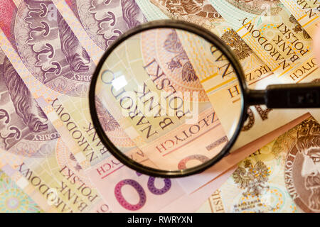 La contraffazione di denaro concetto. Zloty polacco banconote moneta e lente di ingrandimento Foto Stock