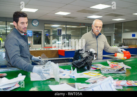 I lavoratori di sesso maschile di riciclaggio di smistamento su nastro trasportatore Foto Stock
