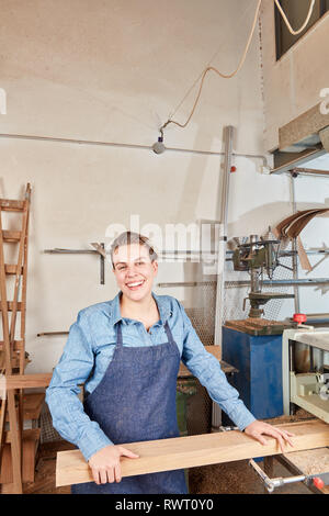 Ridendo giovane donna come falegname apprendista lavora con il legno in corrispondenza della macchina levigatrice Foto Stock
