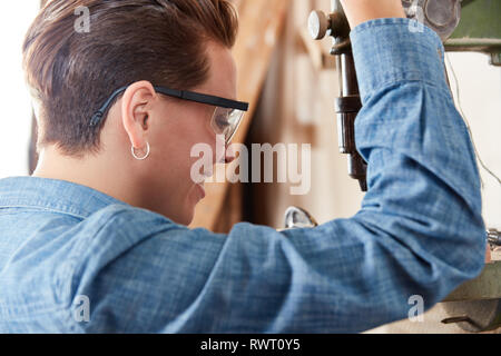 Giovane donna come un falegname apprendista lavora sul trapano in officina Foto Stock
