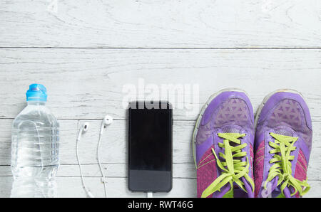 Sport laici piatto scarpe viola, smartphone e allenamento attrezzature su bianco sullo sfondo di legno con copyspace per il tuo testo. Concetto di uno stile di vita sano e Foto Stock